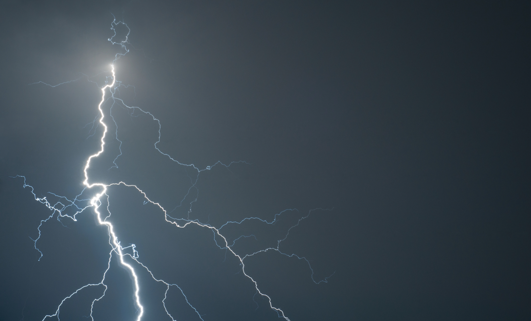 A flask of lightning with multiple branches on a flat grey background.