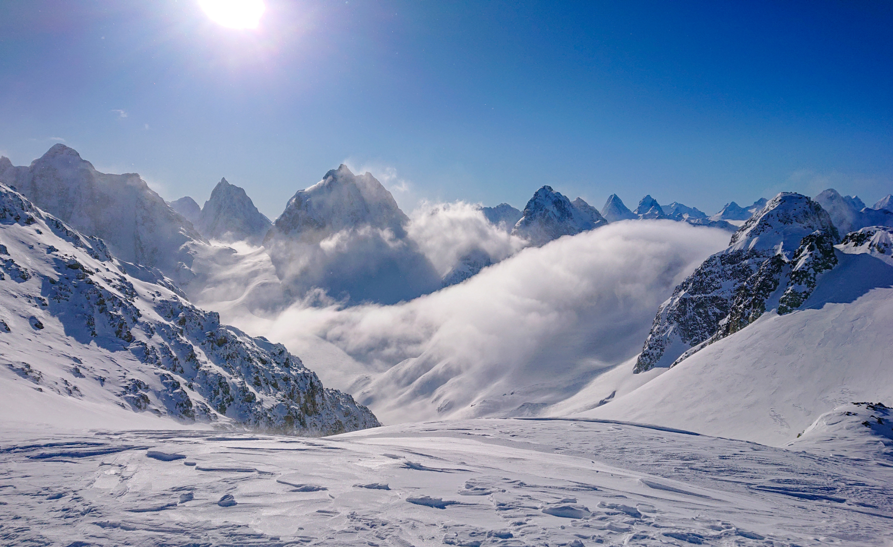 Avalanche between large snowy mountains with a clear blue sky