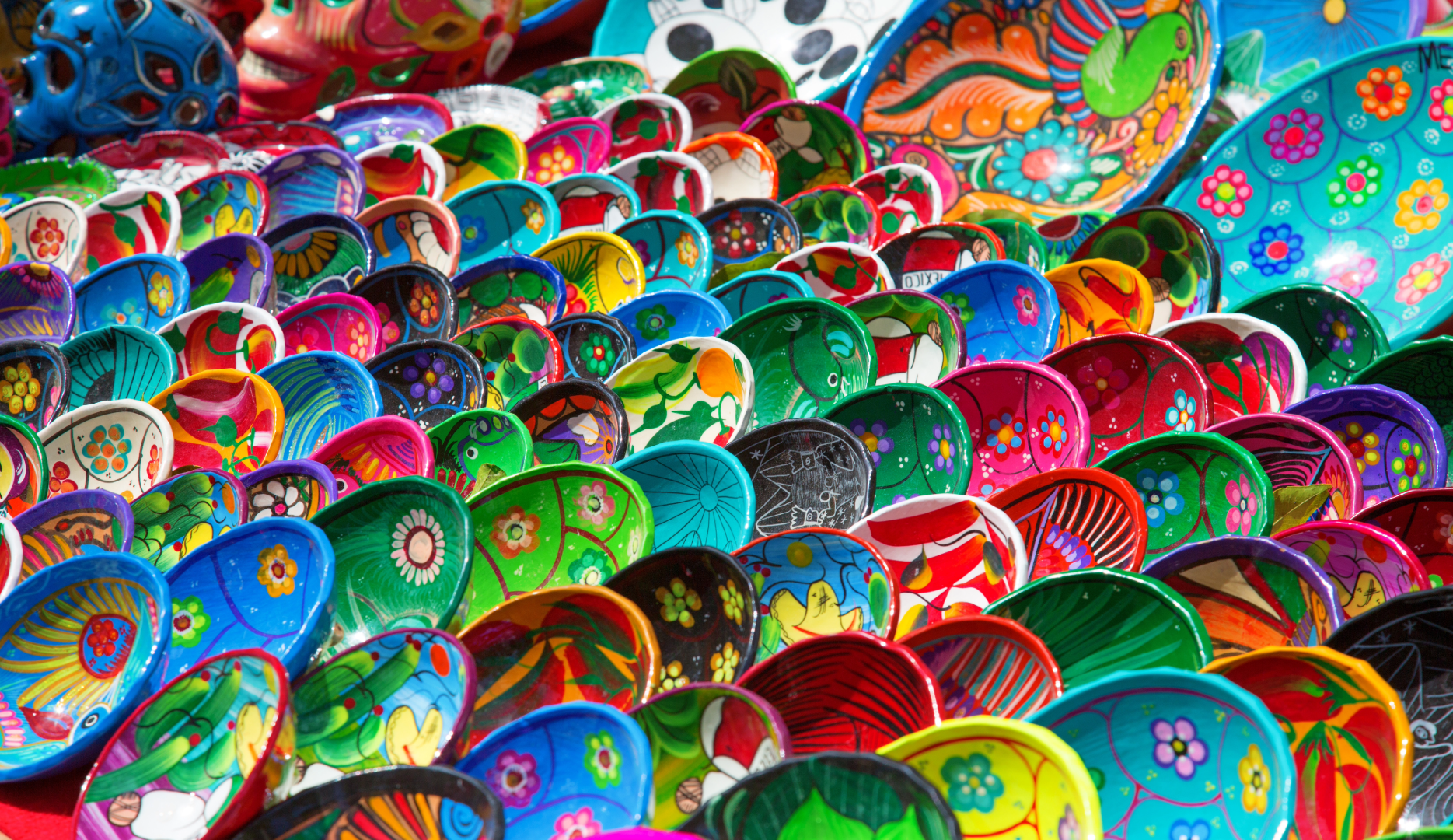 Assortment of colourful small dish highly decorated souvenirs.